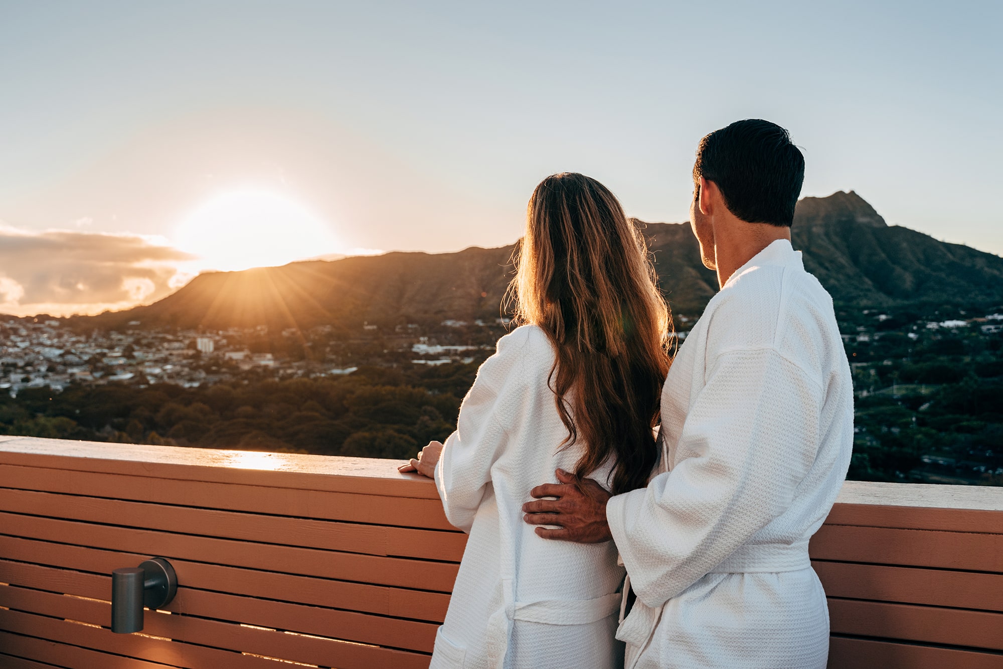 Couple in robes on balcony watching sunset